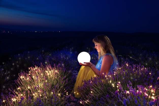 La ragazza tiene la luna tra le mani. campo di lavanda di notte.