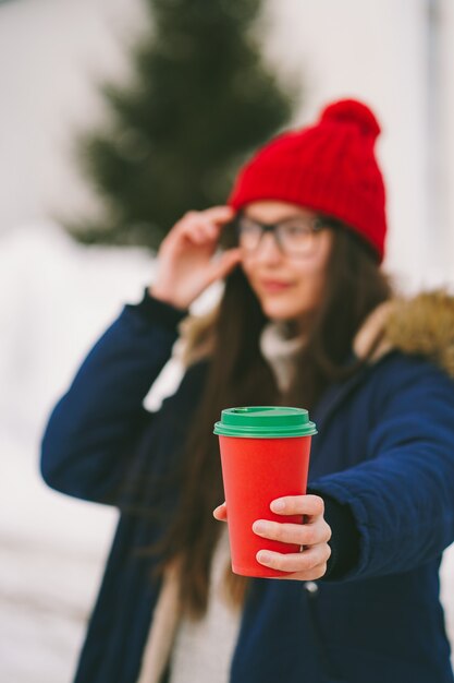 Girl holds out a red paper cup to the camera