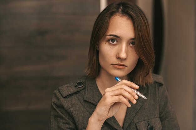 Foto la ragazza tiene una penna e guarda nella telecamera