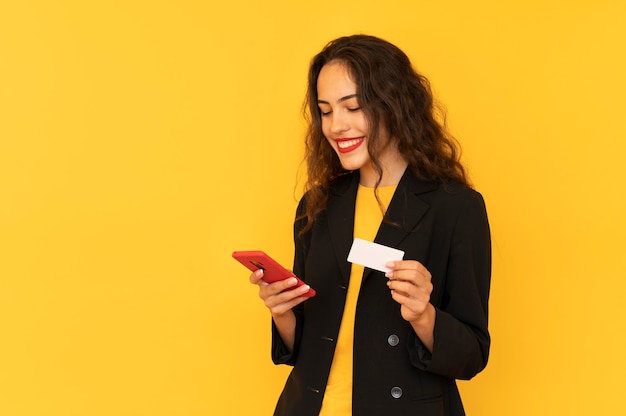 La ragazza tiene il telefono e la carta di credito effettua il pagamento in linea