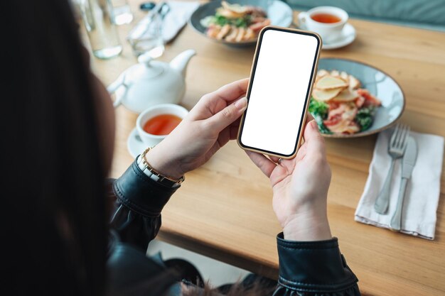 女の子は、食べ物の背景に空白の隔離された画面で彼女の手に電話を持っています