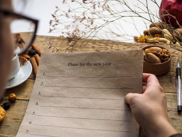 The girl holds a piece of paper with plans for the new year in her hand.