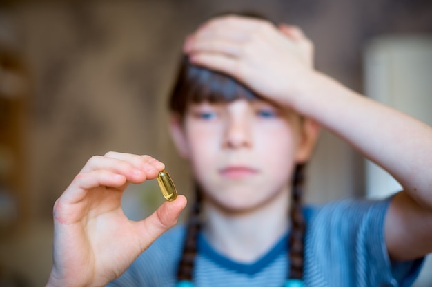Photo girl holds a pill in her hand, headache and cold