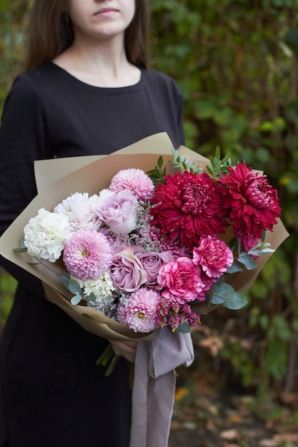 Girl holds pink and purple toned bouquet in vintage style outdoors opposite of the park