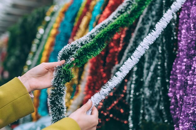 The girl holds the Rain in her hands. Christmas New Year decorations on the tree.