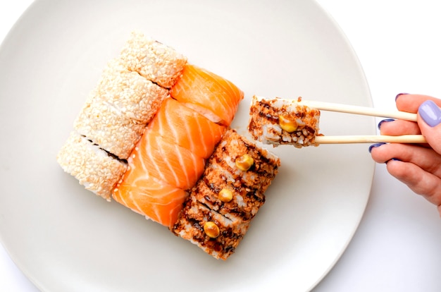 girl holds a roll with chopsticks.