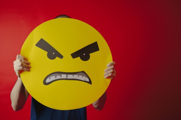 The girl holds a sign in front of her a yellow emoticon of emotions