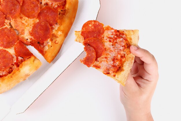 A girl holds a slice of pepperoni pizza on white. Top view.