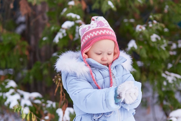 少女は冬の日に雪を手に持っています。