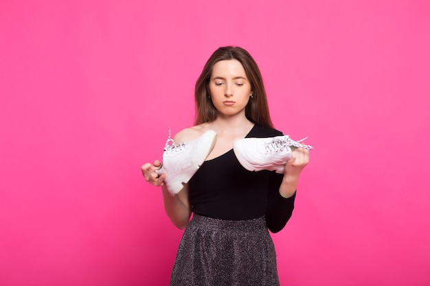 Girl holds stinky sneakers and closes her hand with her nose\
smell of shoes