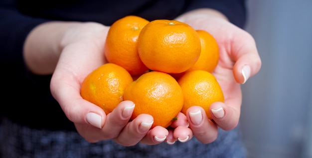 The girl holds tangerines in her hands. Consumption of fruits rich in vitamins