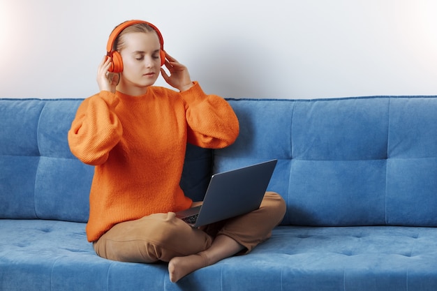 Girl at home on the couch listening to music online