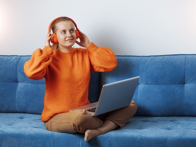 Ragazza a casa sul divano che ascolta musica online