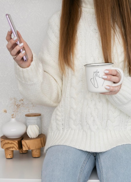 自宅でカップを手にお茶やコーヒーを飲む女の子