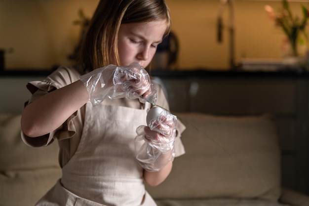 Girl at home in the kitchen dyes eggs for Easter