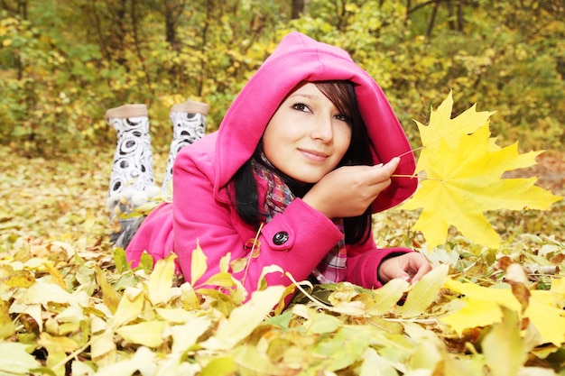 Girl at the hood lies on the yellow the foliage