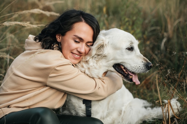 Photo girl hugging a golden retriever dog in the field