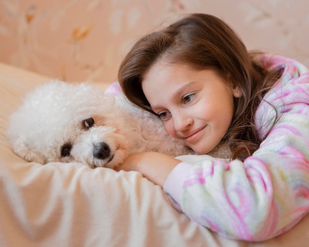 Девушка обнимает собаку в постели
