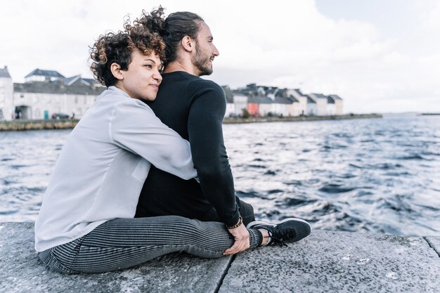 Girl hugging her partner  back with the  sea out of focus