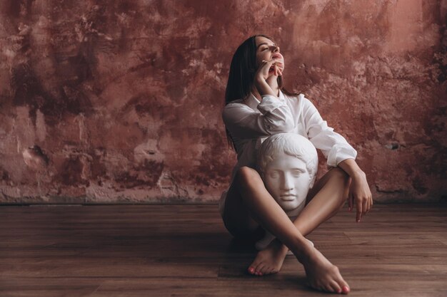 a girl hugging and kissing a white plaster statue of the head of an ancient Greek philosopher