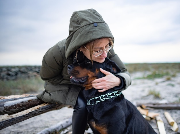 Girl hugging a Rottweiler dog on the beach