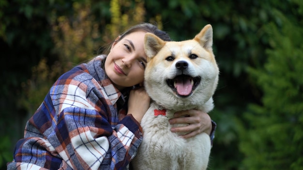 少女は犬を抱きしめ、頭を彼女の上に置き、カメラを見ます