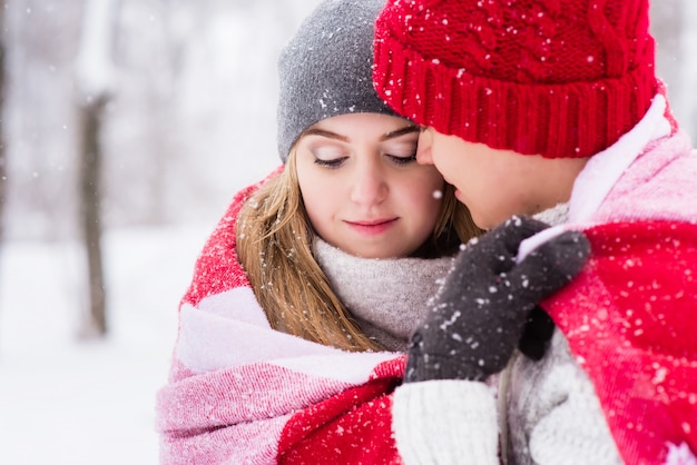 Girl in hugs of her boyfriend in winter forest