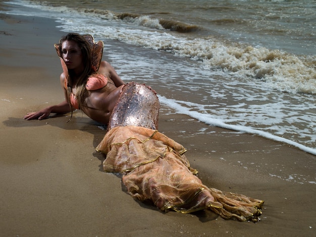 The girl in the image of a mermaid lying on the beach