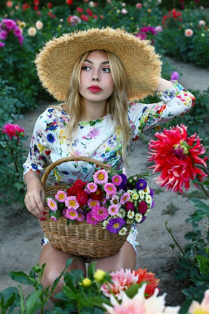 写真 ダリアフィールドに花のバスケットと帽子の少女