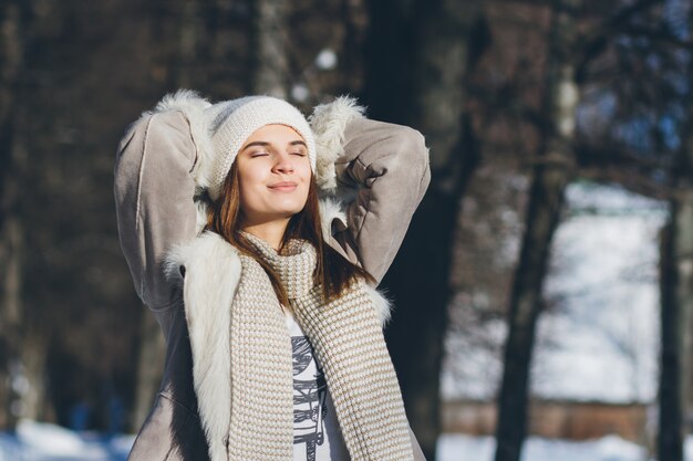 Девушка в шляпе и варежки улыбаются зимой