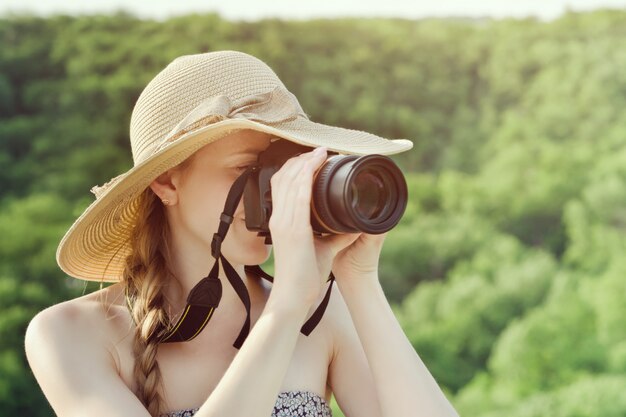 写真 帽子の少女はに対して緑の森の写真を撮る。側面図