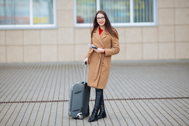 Girl at international airport, luggage and waiting for her flight, view from airport terminal.