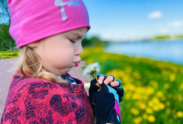 The girl is blowing on a dandelion