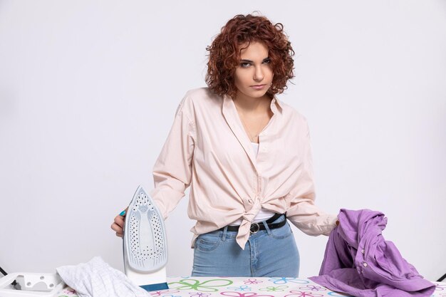 Photo the girl is boiling with anger that she has to iron mens shirts again