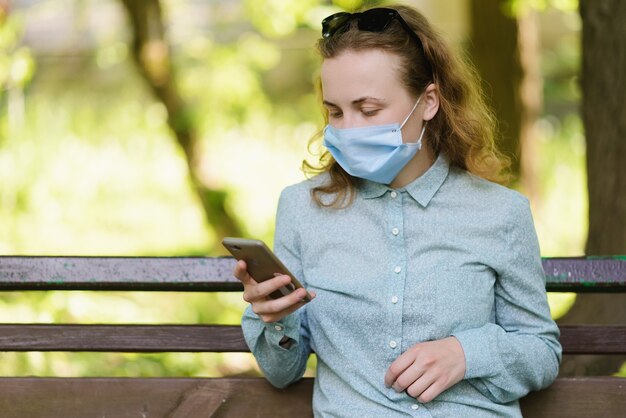 A girl is checking her phone on a sunny summer background