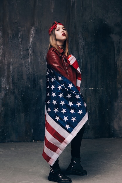 Girl is covered by american flag on dark background