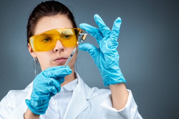 The girl is a doctor, scientist, laboratory assistant holding a bottle with a vaccine, medical tests, laboratory, experiments. Disease treatment immunization chemical analysis.