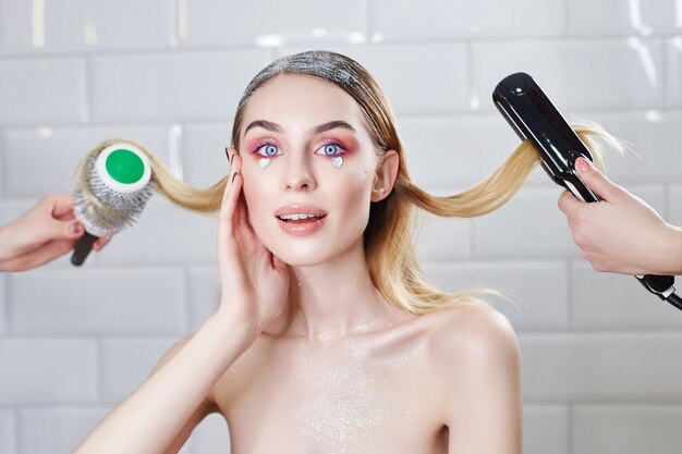 Girl is doing her hair in a beauty salon, hair styling and combing.