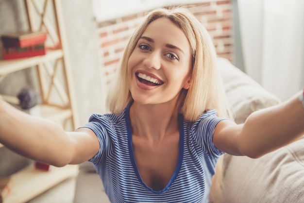 소녀는 selfie을하고 소파에 앉아있는 동안 웃고