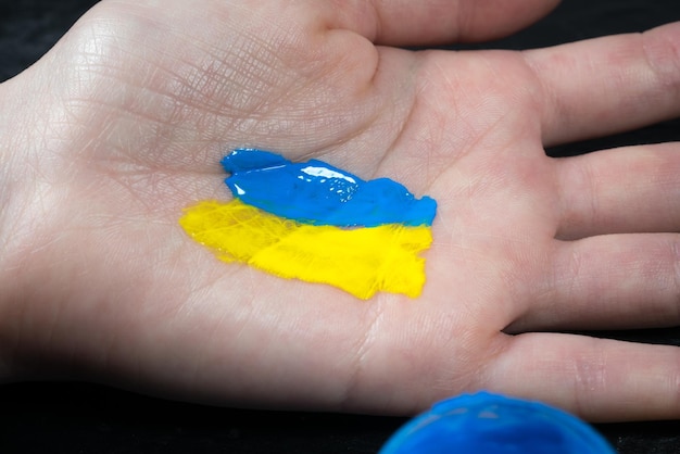 Girl is drawing the flag of Ukraine on her hand Support of the Ukrainian people Stop the war against Ukraine Stop russian invasion