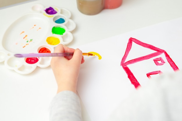 Girl is drawing house and sun.