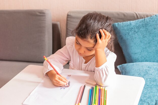 Girl is drawing and painting at a small table