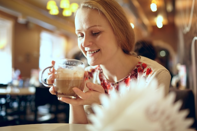 Girl is drinking latte in cafe.