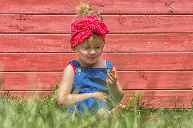 Girl is eating strawberry on a sunny day Crooked funny face Copy space