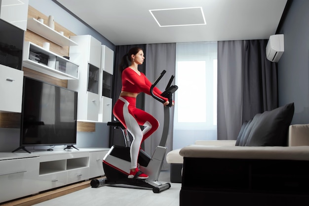 The girl is engaged at home on a stationary bike. She trains with a smart trainer. The concept of active lifestyle at home, health, activity.