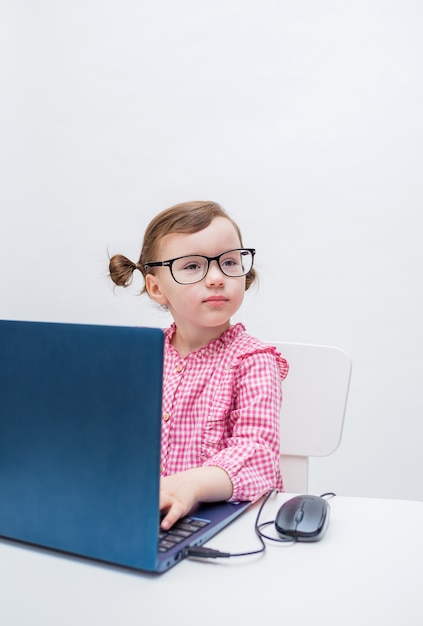 The girl is engaged on a laptop. Distance learning. Playing an office worker.Girl with glasses works on a computer