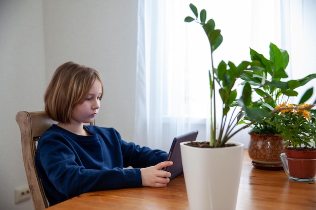 女の子はテーブルでタブレットに従事しています