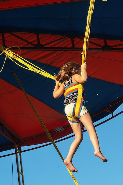 the girl is fastened with elastic bands and jumps on a banjo - a trampoline