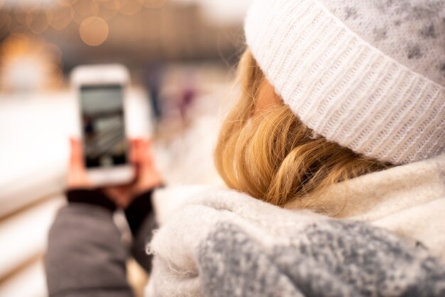 La ragazza sta girando il suo video blog alla fiera di capodanno. sullo sfondo vediamo una pista di pattinaggio