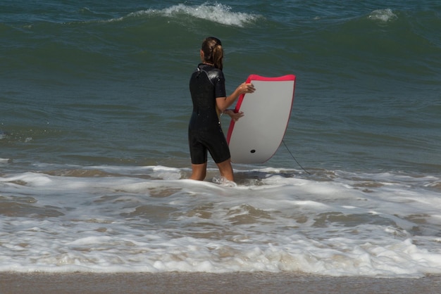 Girl is getting to go into water to go surfing